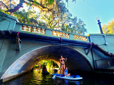 Women on paddle board under small bridge