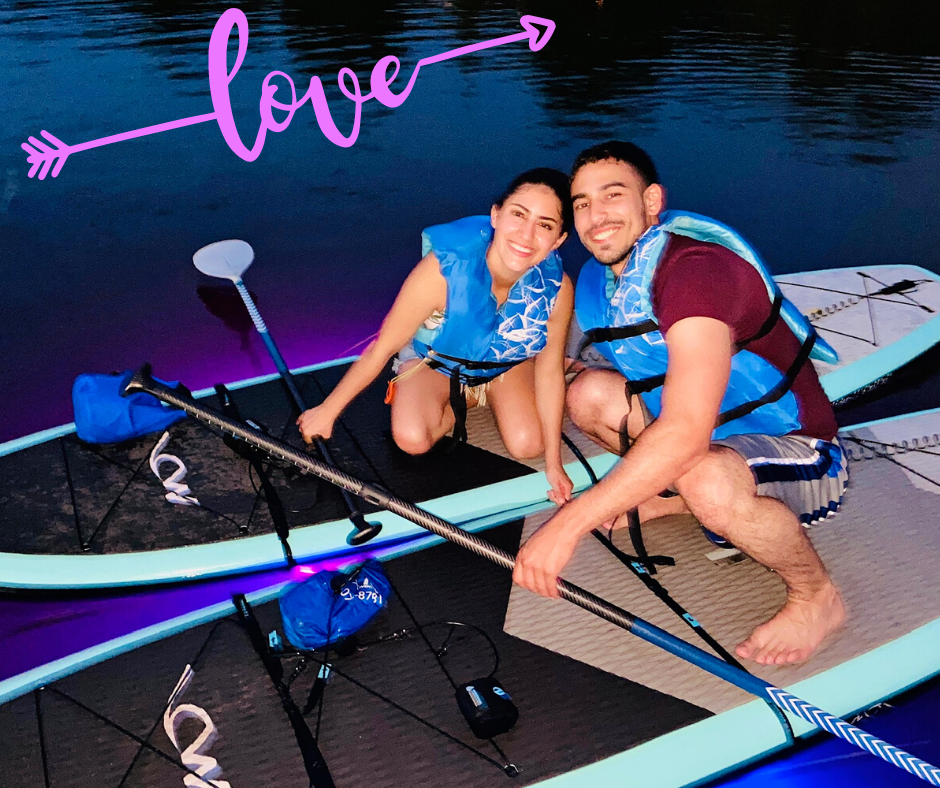 Couple on paddle boards with neon lights