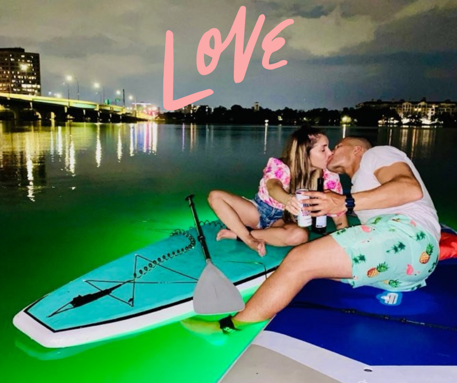 Kissing couple on paddleboards with glowing lights
