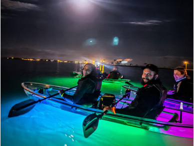 Couple in clear glowing kayak in the dark