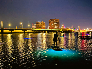 Nighttime paddleboard with neon glow in the water